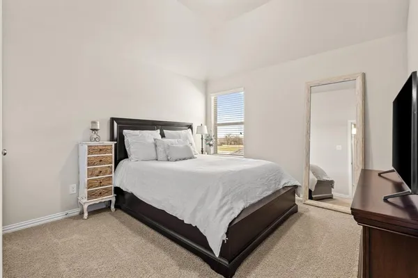 a bedroom with a bed and a flat tv screen on a dresser