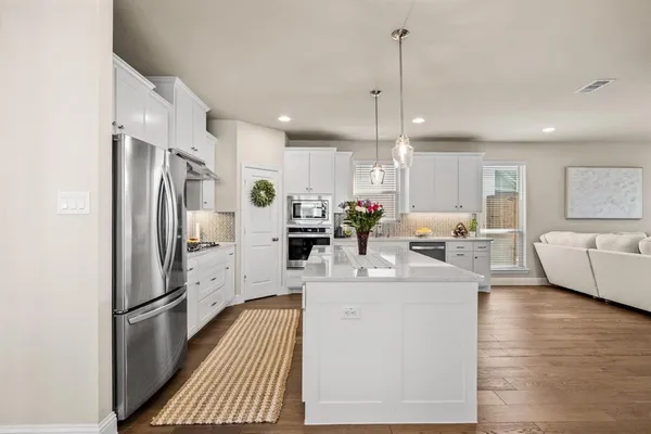 a kitchen with stainless steel appliances a refrigerator sink and white cabinets