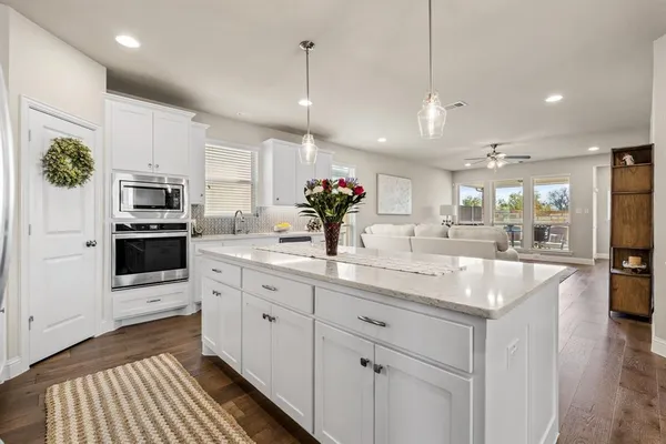 a kitchen with stainless steel appliances kitchen island granite countertop a sink and a refrigerator