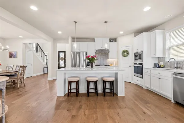 a kitchen with stainless steel appliances granite countertop a table chairs stove a sink dishwasher and cabinets with wooden floor