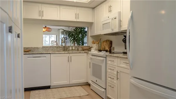 a kitchen with granite countertop white cabinets and white appliances