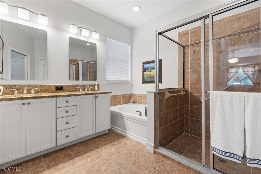 15035 Balmoral Loop Fort Myers, FL 33919 - Photo 30 of 39 a spacious bathroom with a granite countertop sink a mirror a shower and a bathtub