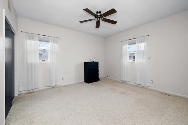an empty room with windows and fan