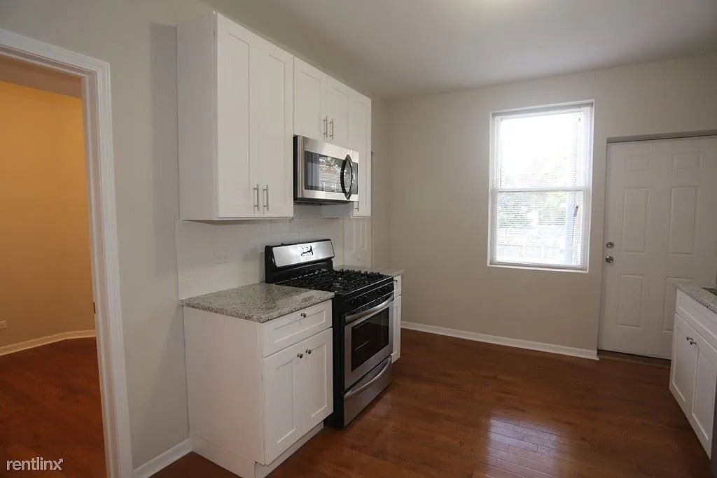3916 West Altgeld Street, Unit 1 Chicago, IL 60647 - Photo 3 of 18 a kitchen with stainless steel appliances granite countertop a stove a sink and a microwave