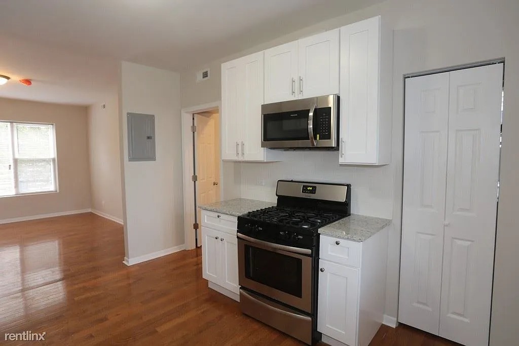 3916 West Altgeld Street, Unit 1 Chicago, IL 60647 - Photo 5 of 18 a kitchen with white cabinets and black appliances