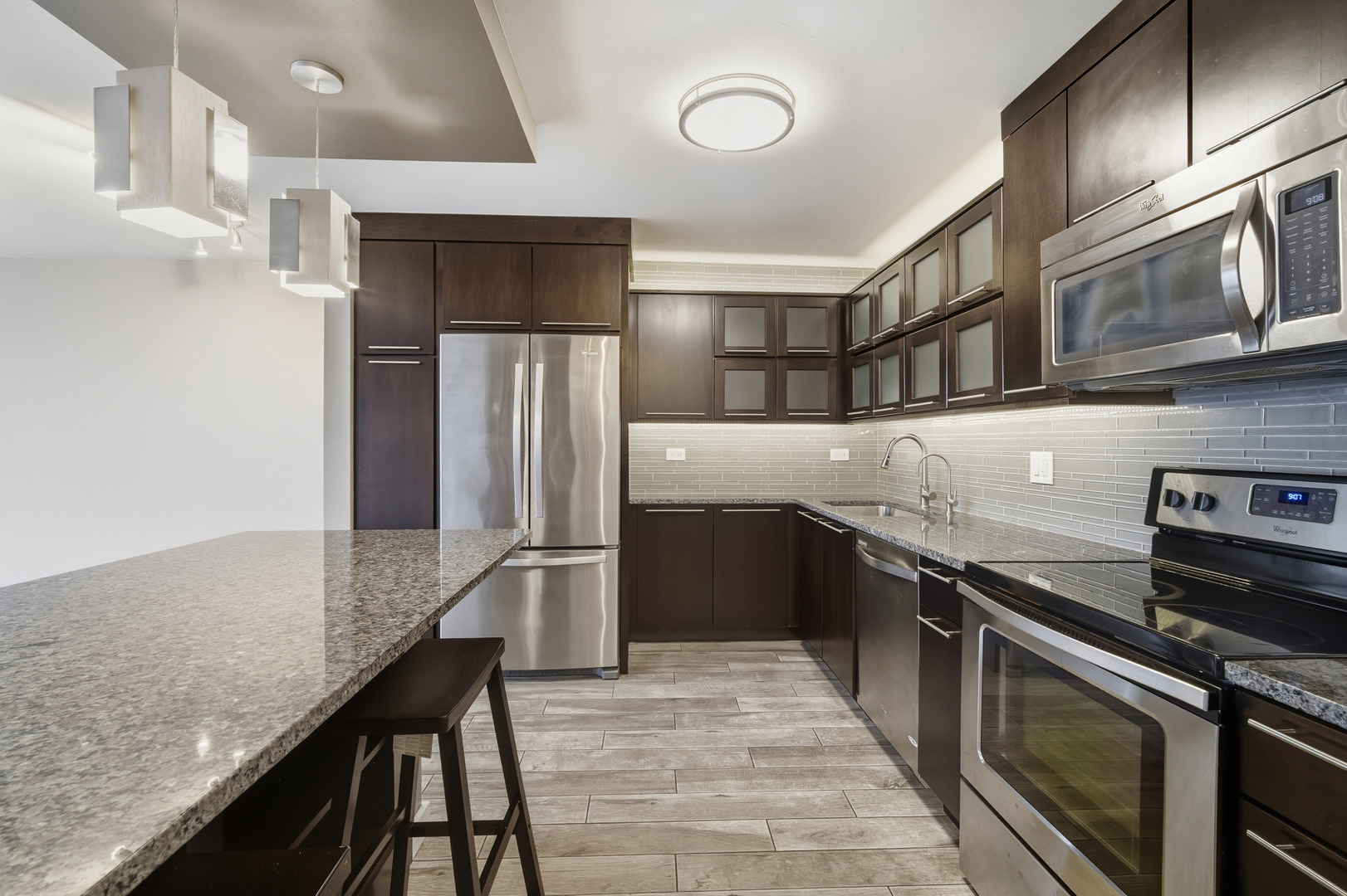 5455 North Sheridan Road, Unit 2611 Chicago, IL 60640 - Photo 5 of 26 a kitchen with stainless steel appliances granite countertop a refrigerator a stove and a sink with wooden floor