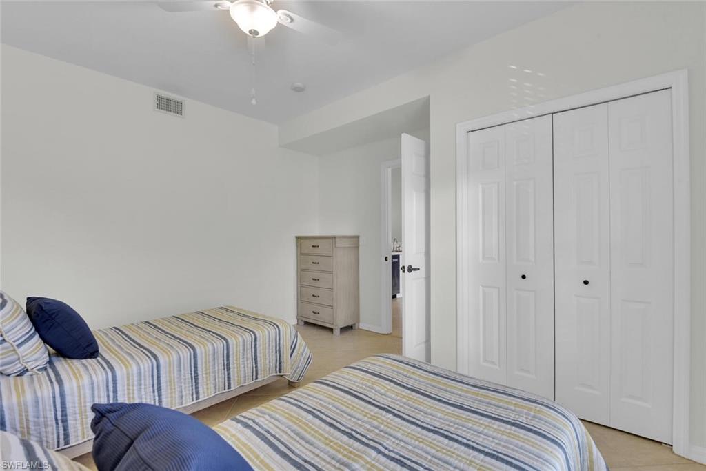 9165 Celeste Drive, Unit 3303 Naples, FL 34113 - Photo 16 of 26 a bedroom with two beds and a chandelier