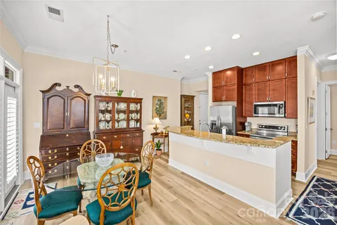 a large kitchen with stainless steel appliances granite countertop a stove a refrigerator a oven a dining table and chairs with wooden floor