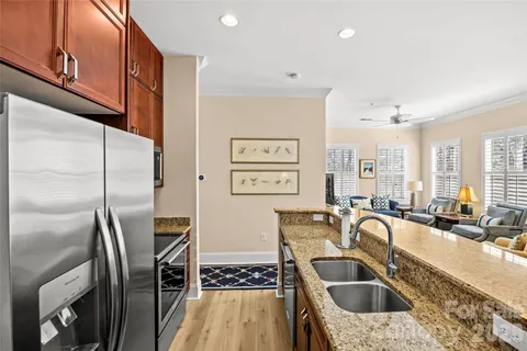 a kitchen with stainless steel appliances granite countertop a sink a refrigerator a stove a washer dryer and a dining table