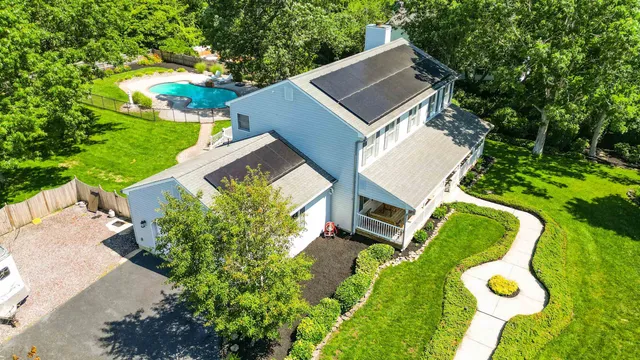 an aerial view of a house with a yard and trees all around
