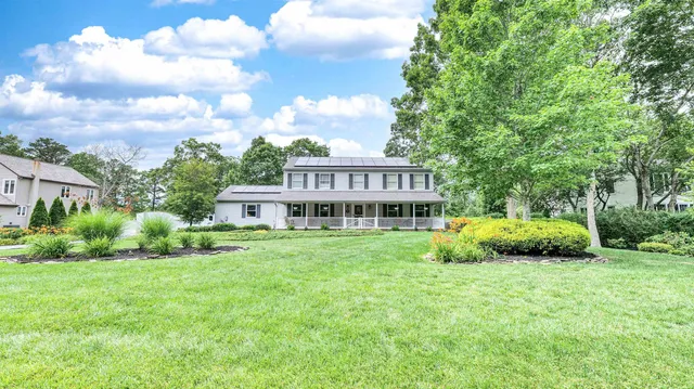 a view of a house with a big yard and large trees