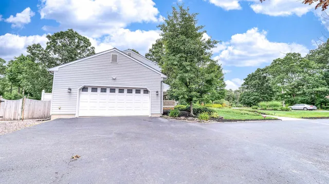 a view of a house with a small yard and large trees