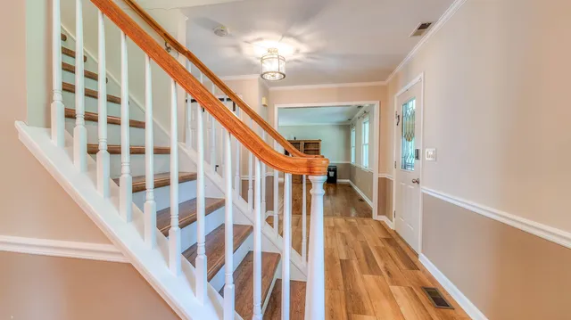 a view of staircase with lots of frames on wall and wooden floor