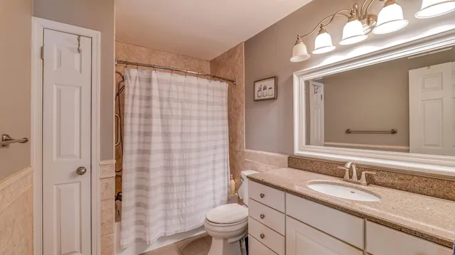 a bathroom with a granite countertop sink a toilet and a mirror