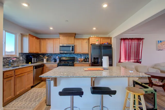 a kitchen with stainless steel appliances granite countertop a refrigerator a stove a sink dishwasher and white cabinets with wooden floor