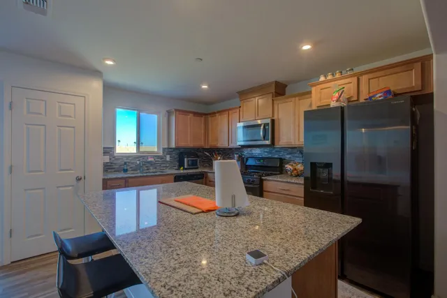 a kitchen with stainless steel appliances granite countertop a sink refrigerator and cabinets