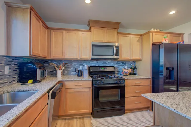 a kitchen with stainless steel appliances granite countertop a stove a sink and a microwave