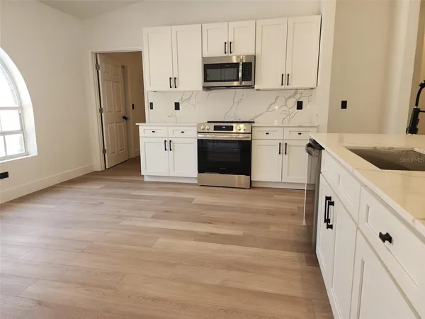 a kitchen with stainless steel appliances granite countertop white cabinets and window