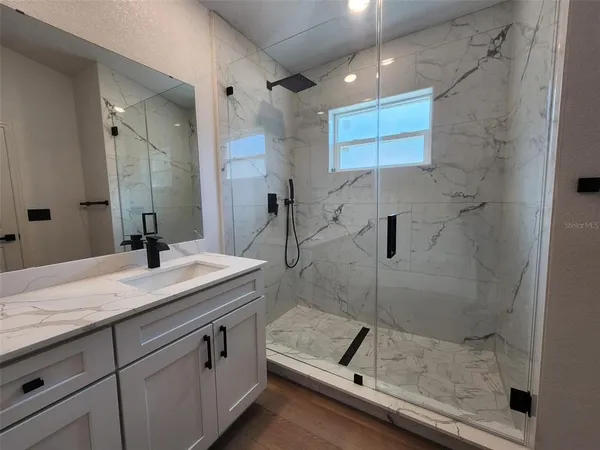 a bathroom with a granite countertop sink a mirror and shower