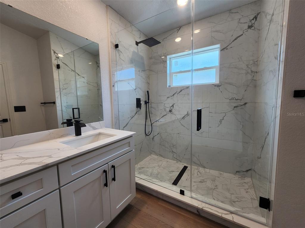 1032 Concert Avenue Spring Hill, FL 34609 - Photo 31 of 35 a bathroom with a granite countertop sink a mirror and shower
