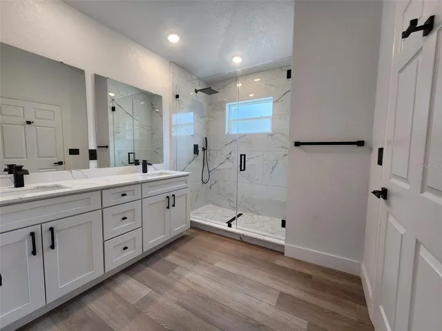 a spacious bathroom with a double vanity sink a large mirror and shower