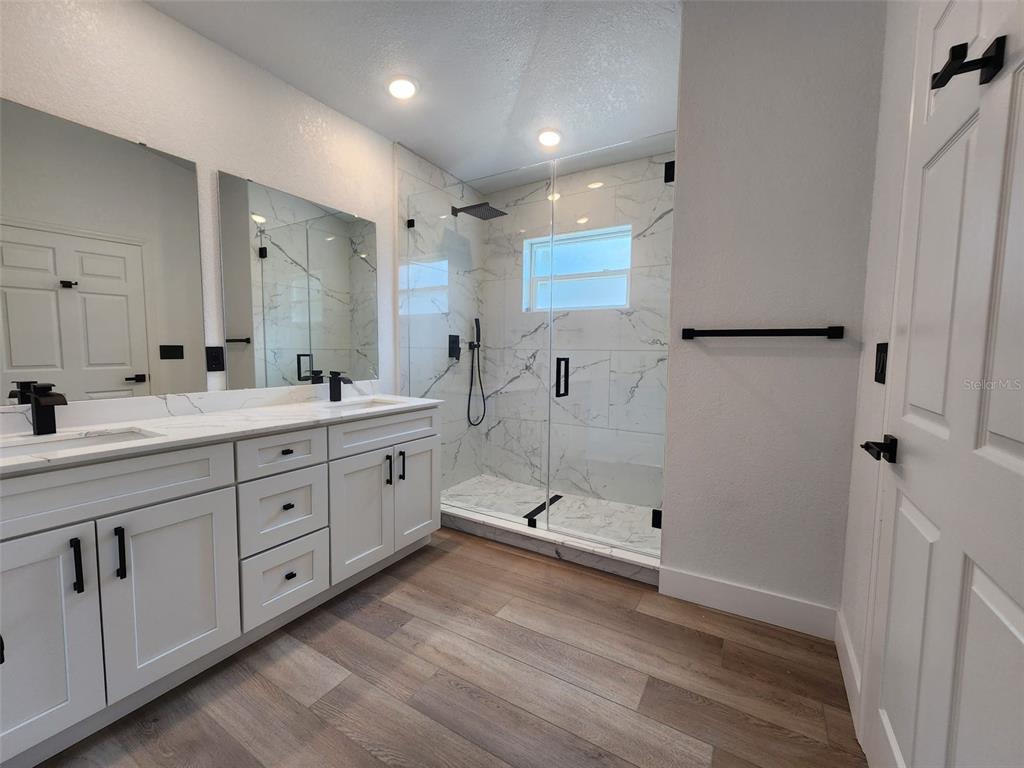 1032 Concert Avenue Spring Hill, FL 34609 - Photo 32 of 35 a spacious bathroom with a double vanity sink a large mirror and shower