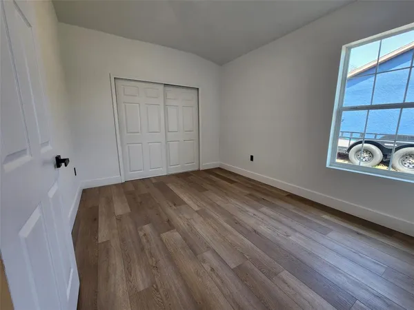 a view of empty room with wooden floor and window