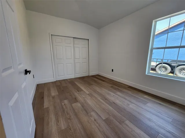 a view of empty room with wooden floor and window