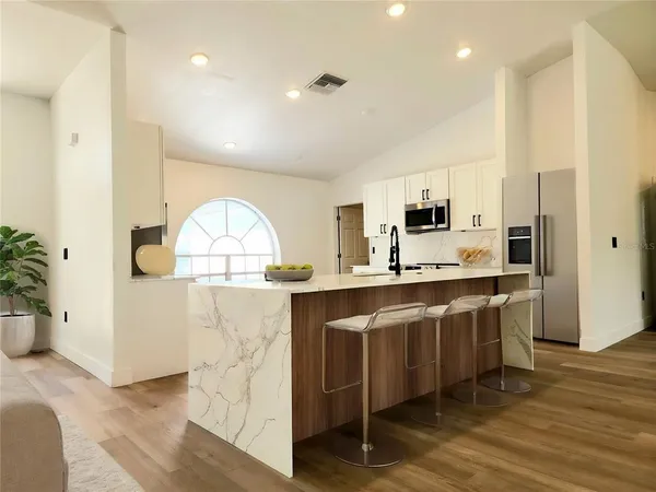 a large kitchen with stainless steel appliances a large counter top a stove and a refrigerator