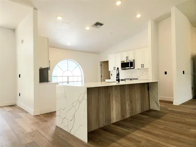 a view of a kitchen with a sink and dishwasher with wooden floor