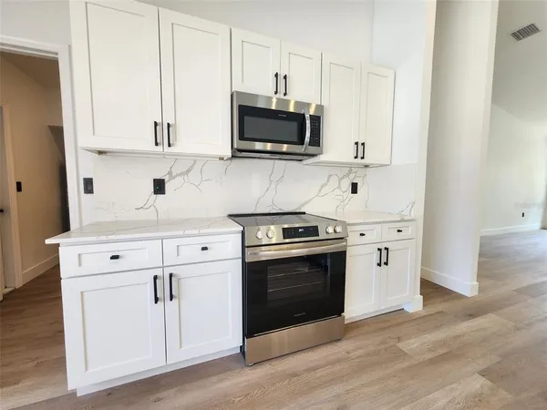 a kitchen with stainless steel appliances white cabinets and a stove top oven