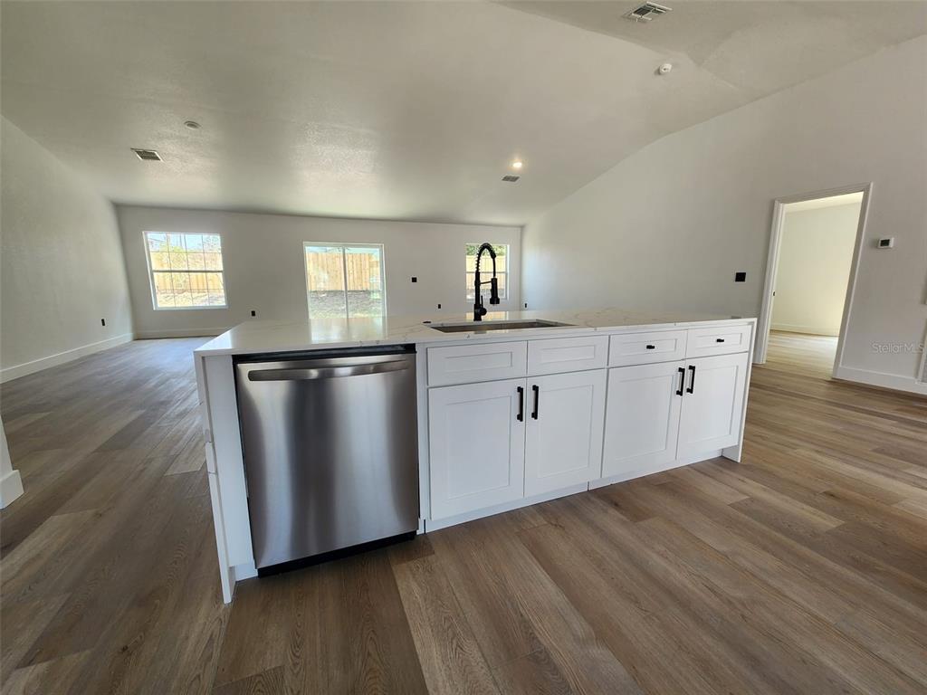 1032 Concert Avenue Spring Hill, FL 34609 - Photo 9 of 35 a kitchen with granite countertop white cabinets and wooden floor