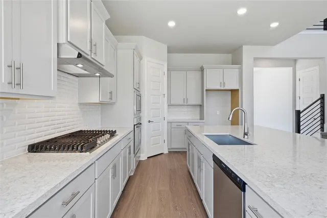 a kitchen with stainless steel appliances granite countertop a sink stove cabinets and wooden floor