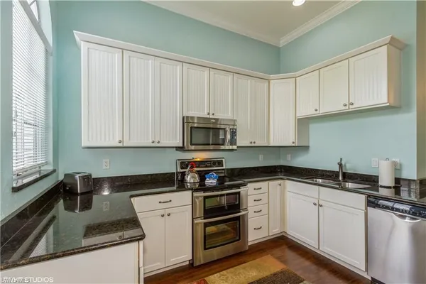 a kitchen with granite countertop white cabinets and white stainless steel appliances