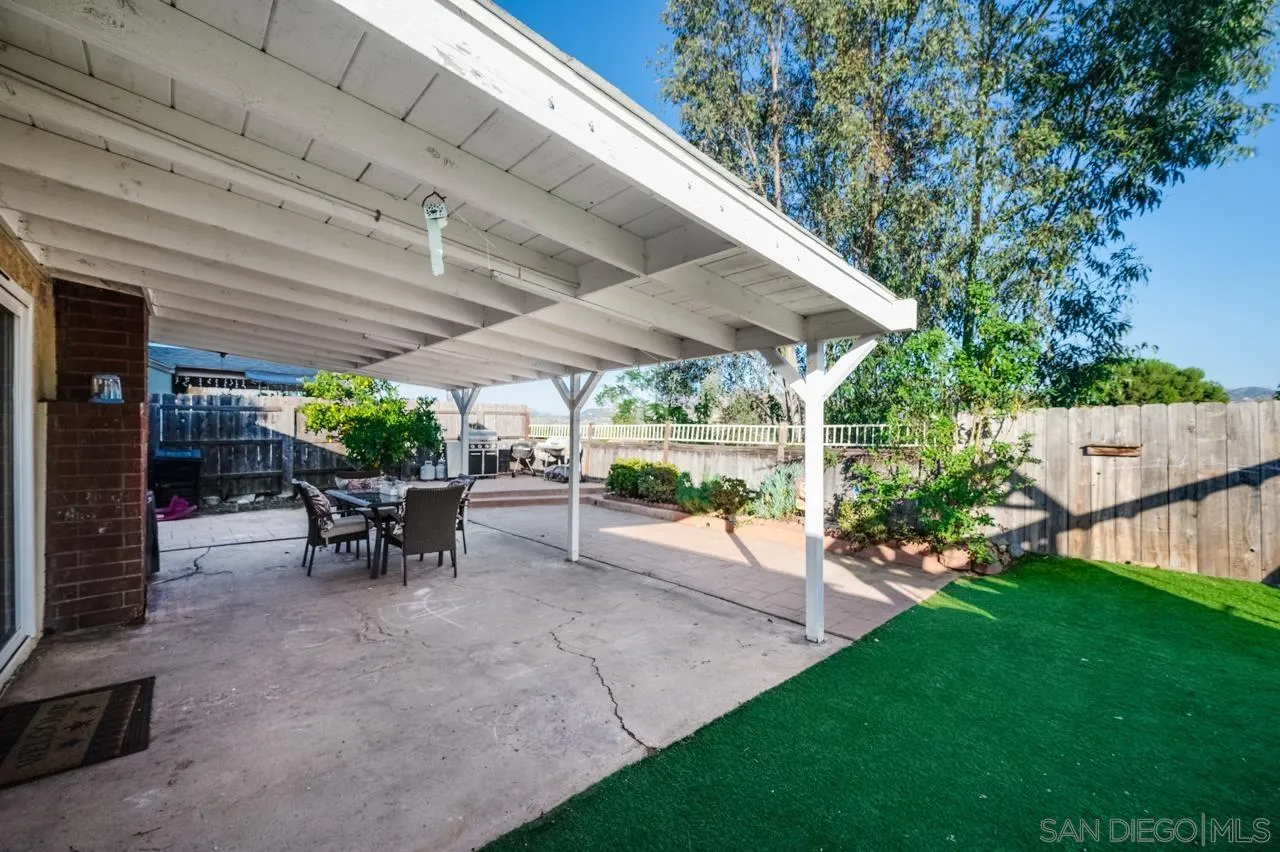 14027 Hermosillo Way Poway, CA 92064 - Photo 29 of 31 a view of a patio with table and chairs potted plants with floor to ceiling window and wooden fence