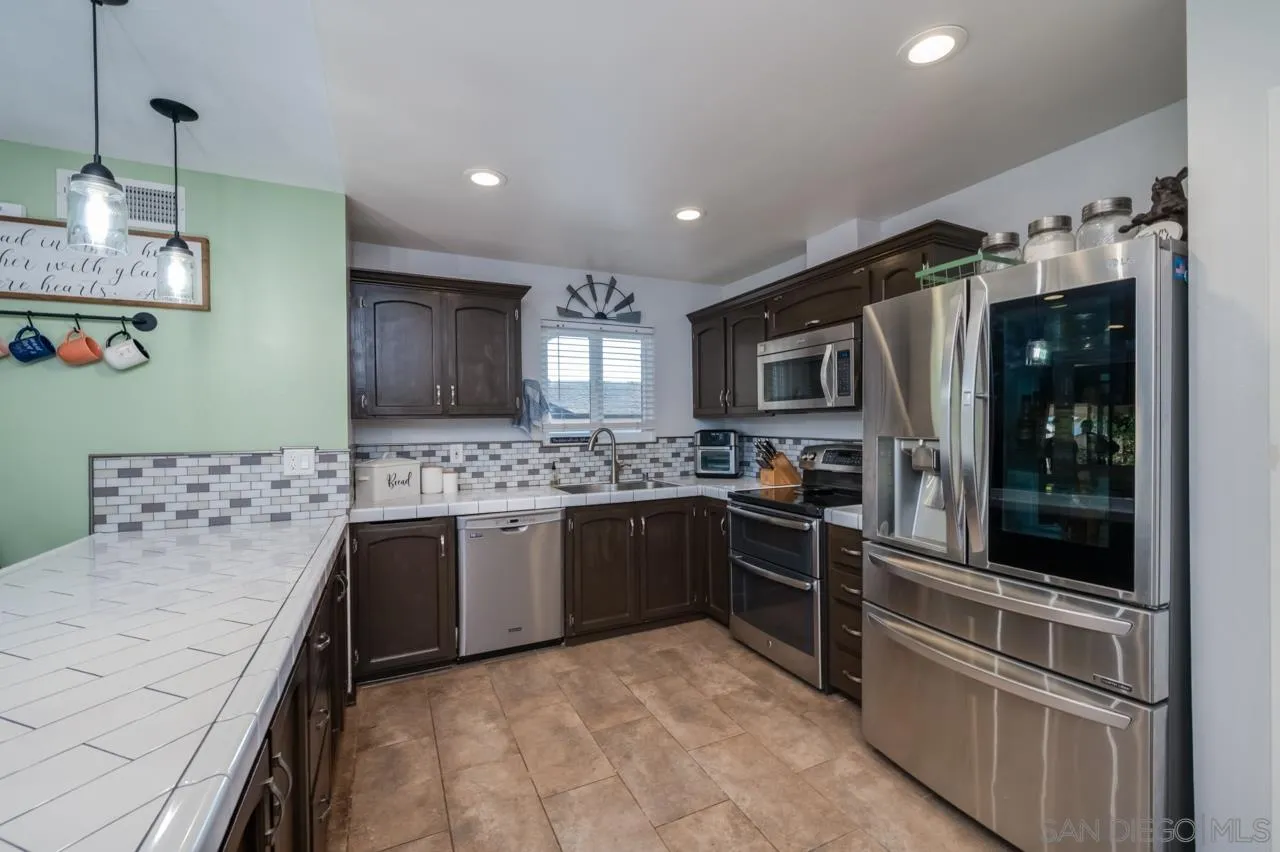 14027 Hermosillo Way Poway, CA 92064 - Photo 10 of 31 a large kitchen with stainless steel appliances granite countertop a stove and a sink