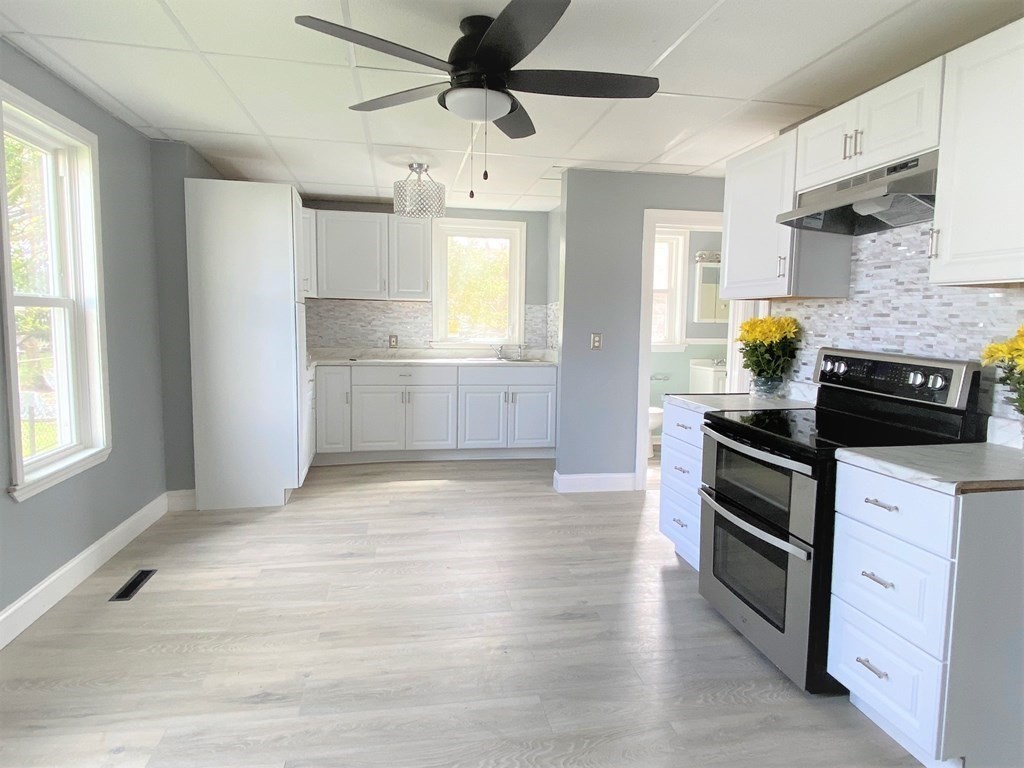 171 Snell Street Fall River, MA 02721 - Photo 7 of 34 a kitchen with stainless steel appliances kitchen island granite countertop a stove a sink and white cabinets with wooden floor