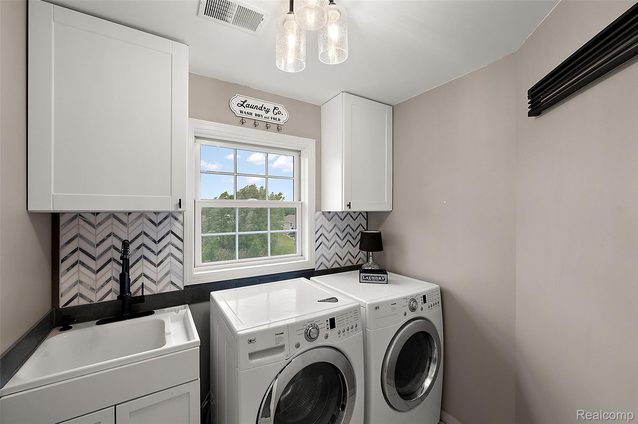 5035 Hidden Ridge Road Metamora, MI 48455 - Photo 40 of 65 Utility room featuring white cabinetry, a sink with a matte black faucet, and a chevron-patterned tile backsplash