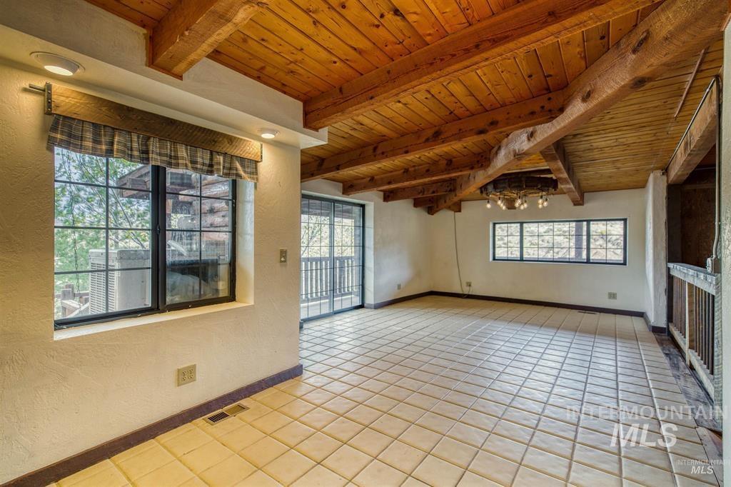 11500 Brownlee Road Sweet, ID 83670 - Photo 14 of 22 Unfurnished room with a wood ceiling with exposed beams, plenty of natural light, light tile patterned floors, and a textured wall