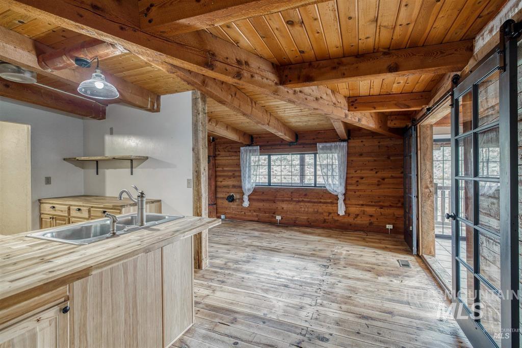 11500 Brownlee Road Sweet, ID 83670 - Photo 17 of 22 Kitchen with light wood finish cabinets, open shelves, wood walls, light wood finished floors, and a wood ceiling with exposed beams