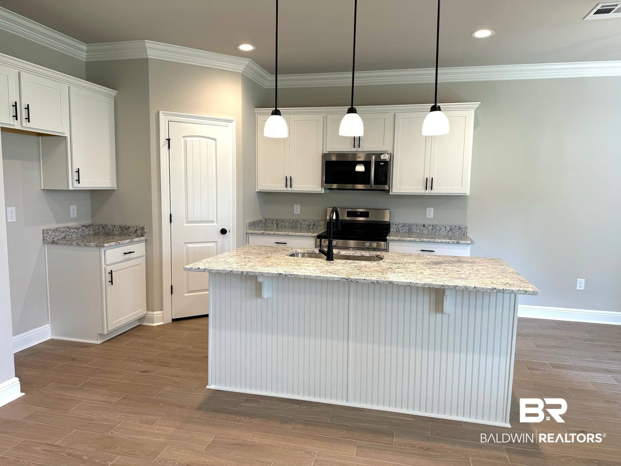 904 Sumter Loop Foley, AL 36535 - Photo 3 of 10 Kitchen featuring white cabinets, stainless steel appliances, a kitchen bar, and an island with sink