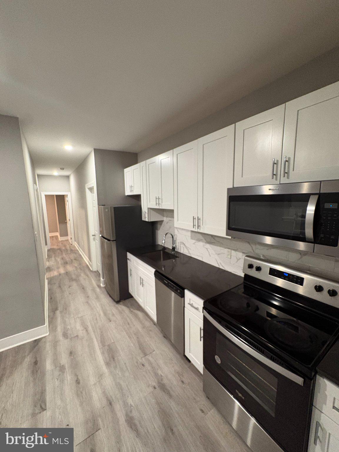 1813 South 23rd Street, Unit 2 Philadelphia, PA 19145 - Photo 4 of 20 a kitchen with stainless steel appliances kitchen island granite countertop a stove a sink and a microwave