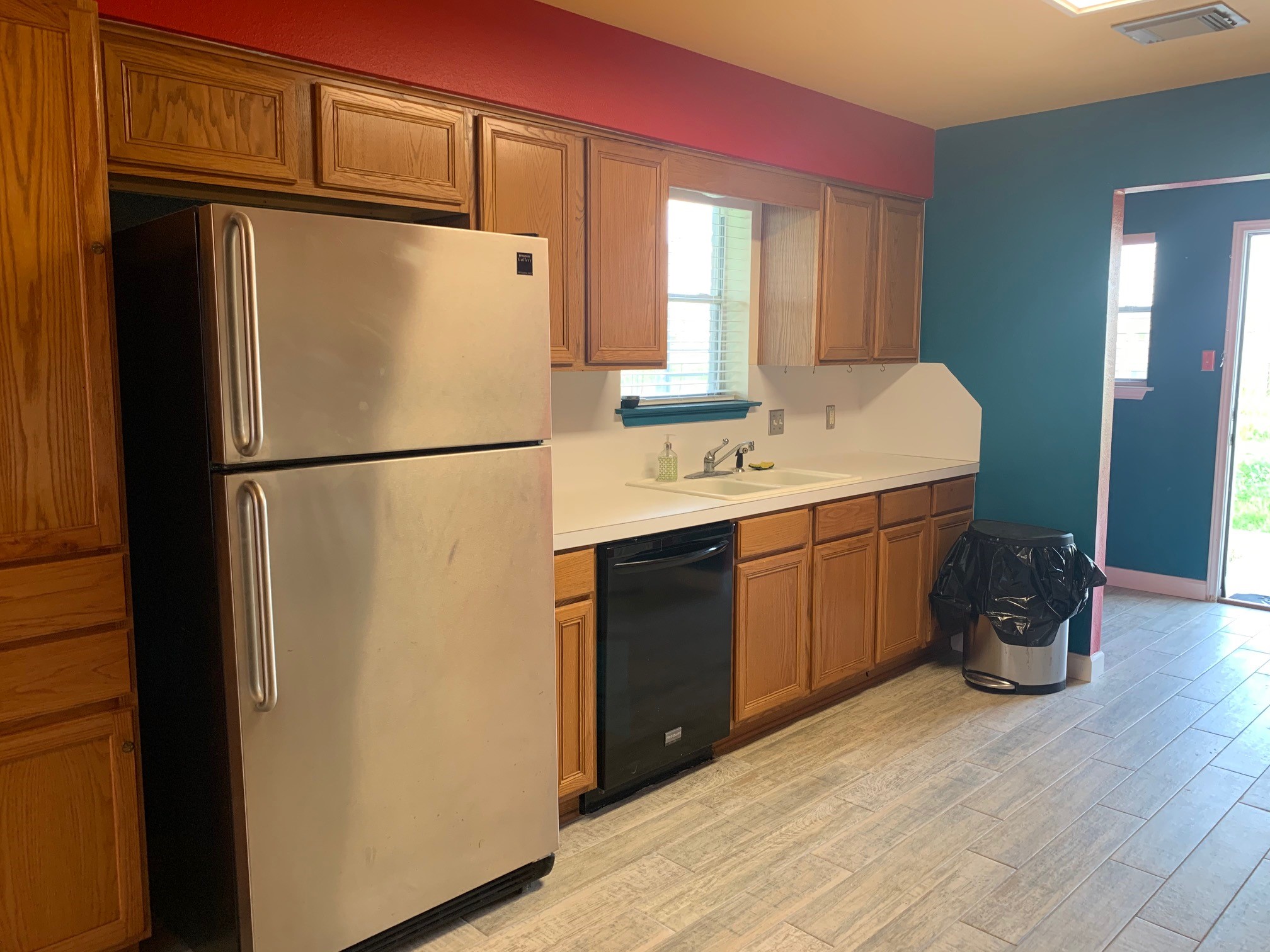 13605 Ralph Ritchie Road Manor, TX 78653 - Photo 12 of 19 Kitchen featuring freestanding refrigerator, light countertops, light wood-style flooring, black dishwasher, and wood finish cabinetry