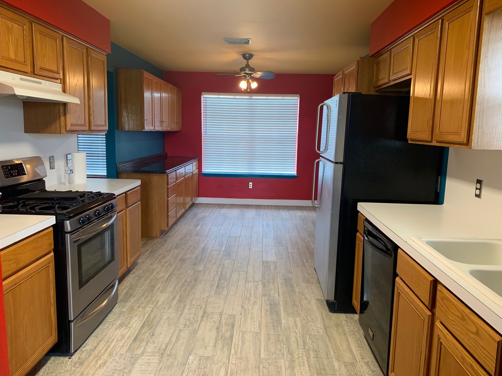 13605 Ralph Ritchie Road Manor, TX 78653 - Photo 10 of 19 Kitchen featuring wood finish cabinets, stainless steel range with gas stovetop, light wood finished floors, light countertops, and a ceiling fan