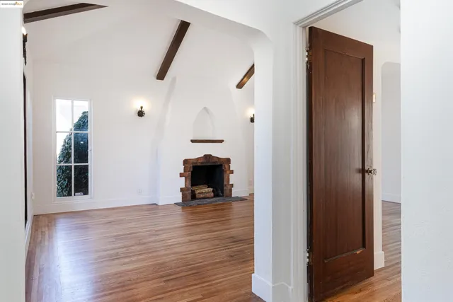 a view of an empty room with wooden floor and a fireplace