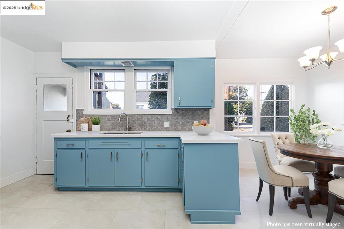 7601 Holly Street Oakland, CA 94621 - Photo 23 of 51 Kitchen with blue cabinets, backsplash, plenty of natural light, and decorative light fixtures