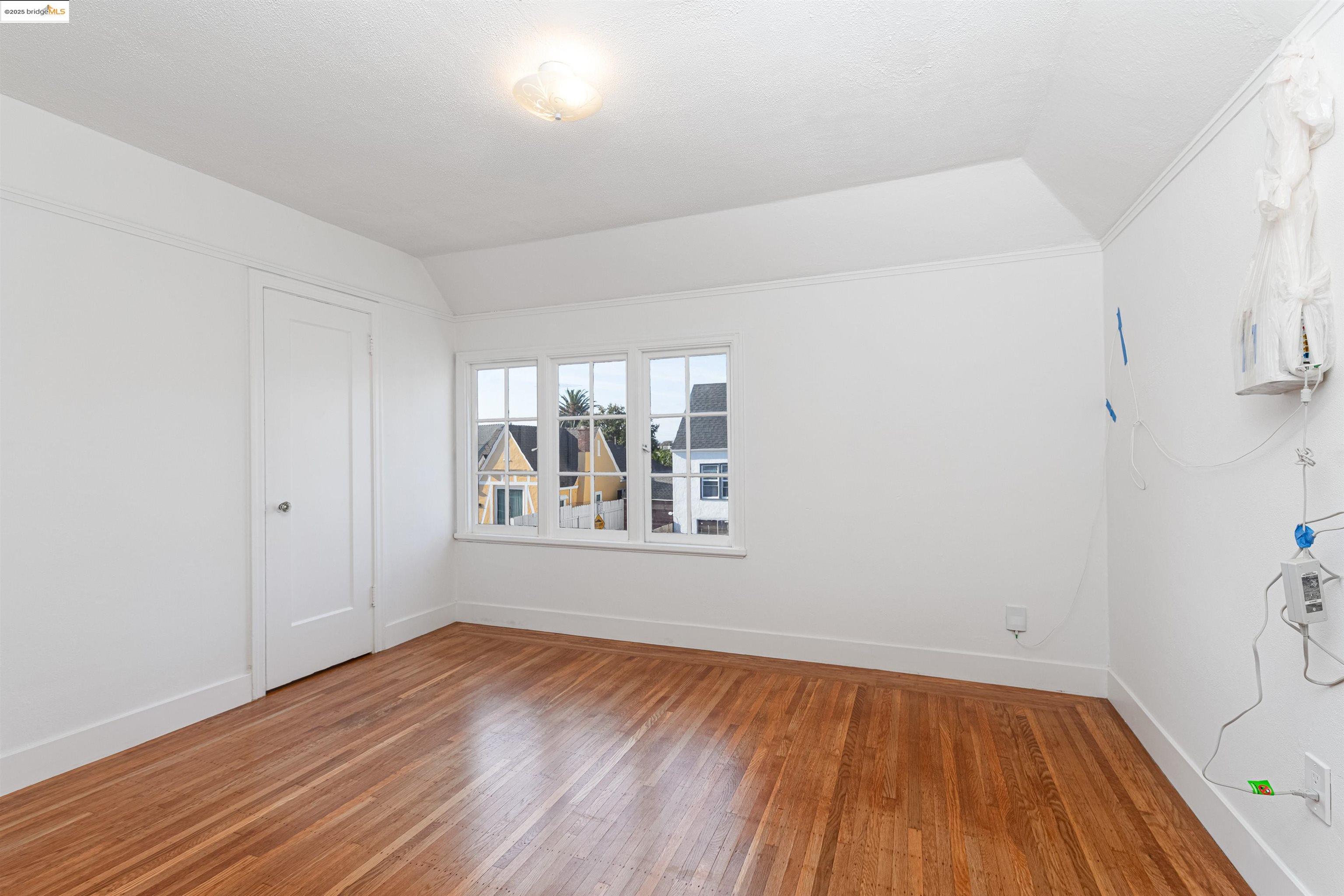 7601 Holly Street Oakland, CA 94621 - Photo 37 of 51 an empty room with wooden floor and windows