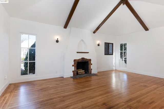 a view of a livingroom with wooden floor a fireplace and windows