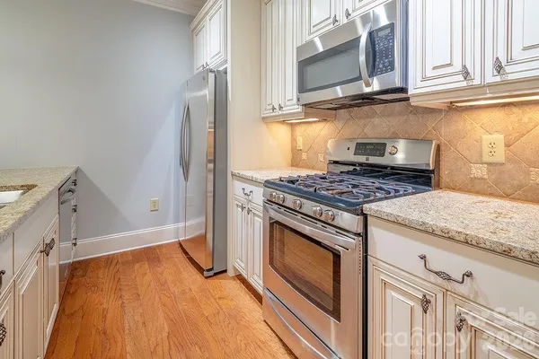 a kitchen with granite countertop cabinets stainless steel appliances and wooden floor