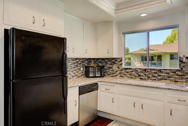 a kitchen with stainless steel appliances granite countertop white cabinets and a refrigerator